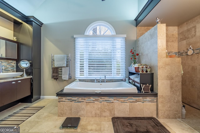 bathroom with tasteful backsplash, vanity, radiator heating unit, tiled bath, and tile patterned flooring