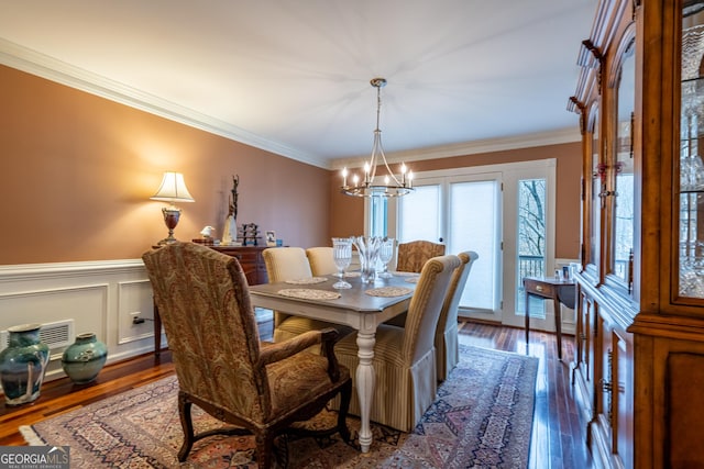 dining room with a notable chandelier, crown molding, and dark wood-type flooring