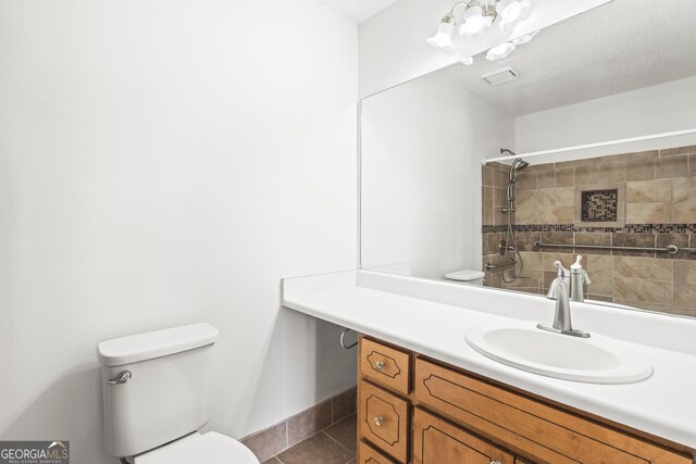 full bathroom with toilet, vanity, a tile shower, and tile patterned floors