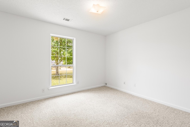 spare room featuring a textured ceiling, carpet, visible vents, and a healthy amount of sunlight