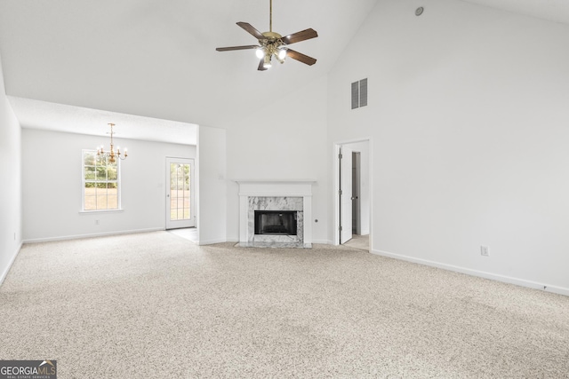 unfurnished living room featuring ceiling fan with notable chandelier, visible vents, a high end fireplace, baseboards, and carpet