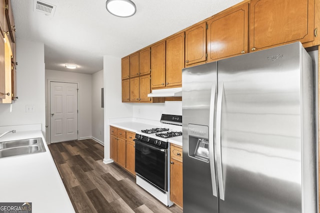 kitchen with visible vents, range with gas stovetop, under cabinet range hood, stainless steel refrigerator with ice dispenser, and a sink