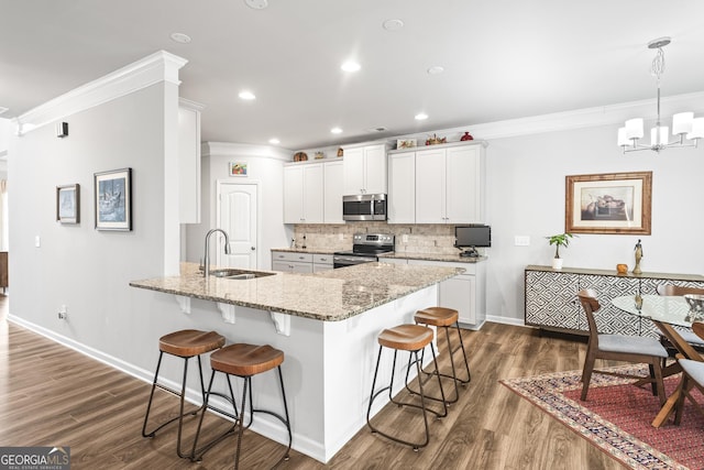 kitchen with ornamental molding, a sink, backsplash, stainless steel appliances, and a breakfast bar area