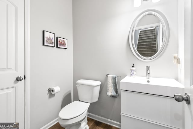 bathroom featuring vanity, toilet, wood finished floors, and baseboards