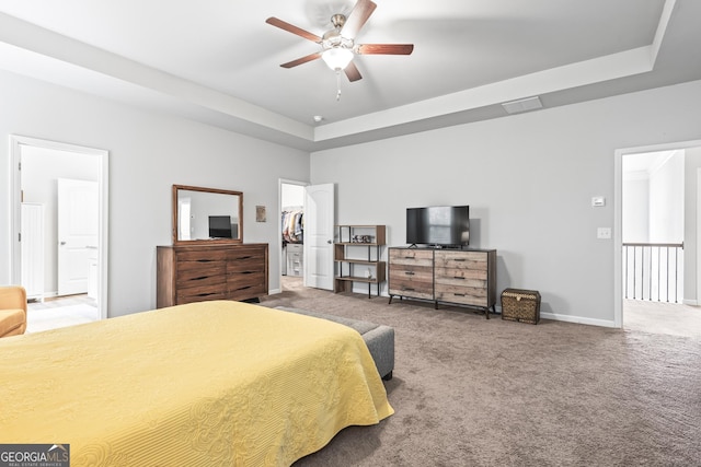 carpeted bedroom with a spacious closet, visible vents, a raised ceiling, and baseboards