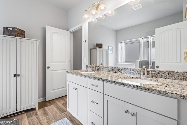 bathroom featuring double vanity, visible vents, wood finished floors, and a sink