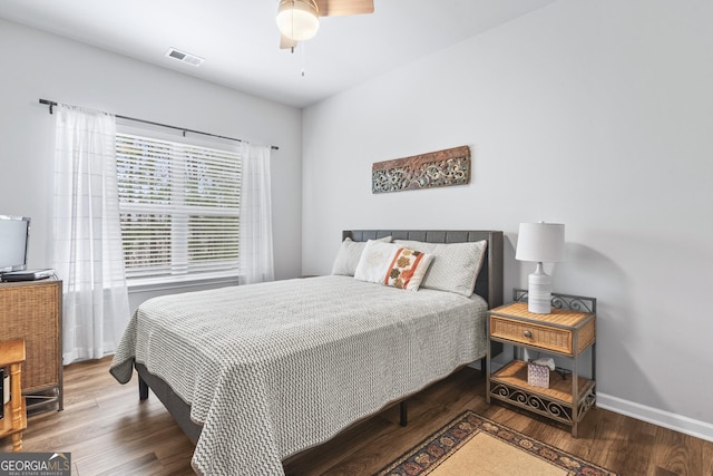 bedroom featuring ceiling fan, visible vents, baseboards, and wood finished floors