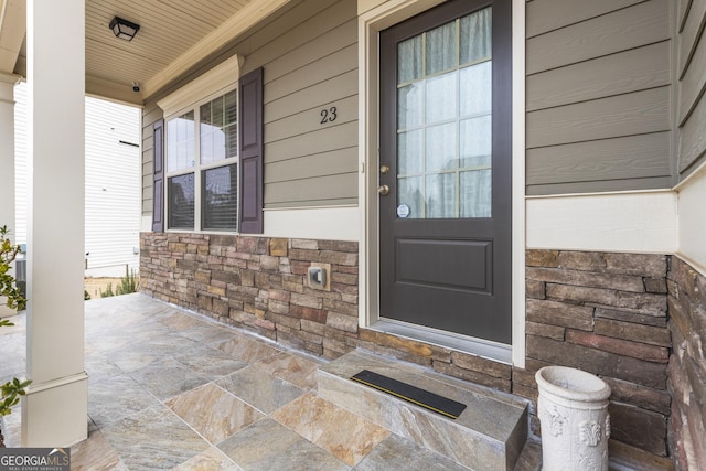 doorway to property featuring stone siding and covered porch