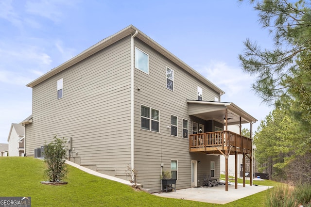 back of property featuring a yard, a wooden deck, and a patio area