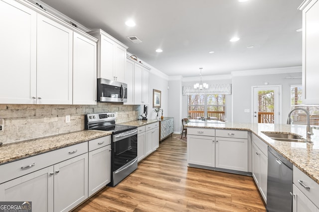 kitchen featuring crown molding, light wood-type flooring, decorative backsplash, appliances with stainless steel finishes, and a sink