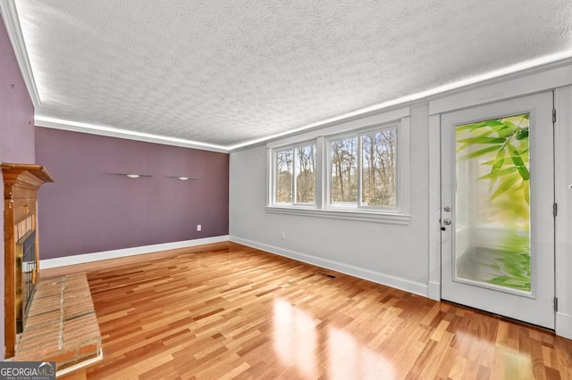 unfurnished living room with a fireplace, a textured ceiling, and light wood-type flooring