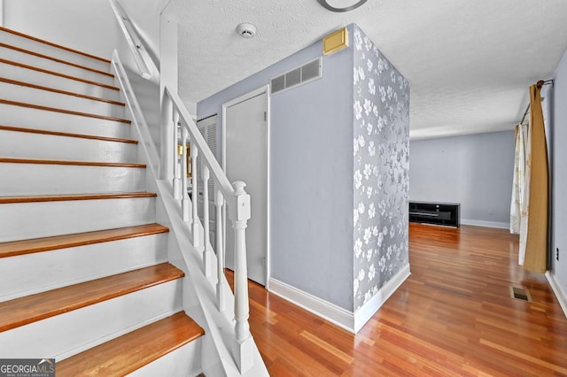 staircase with hardwood / wood-style floors and a textured ceiling