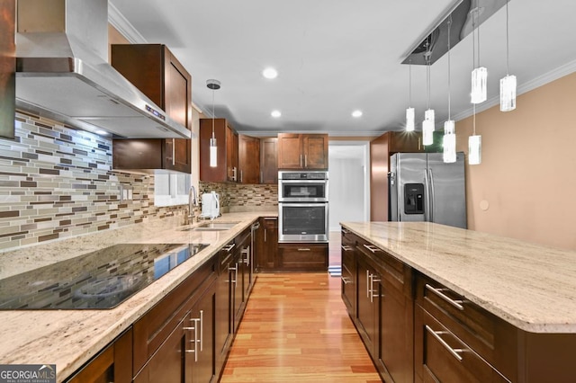 kitchen with sink, appliances with stainless steel finishes, light stone countertops, pendant lighting, and range hood