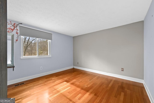 spare room with hardwood / wood-style flooring and a textured ceiling