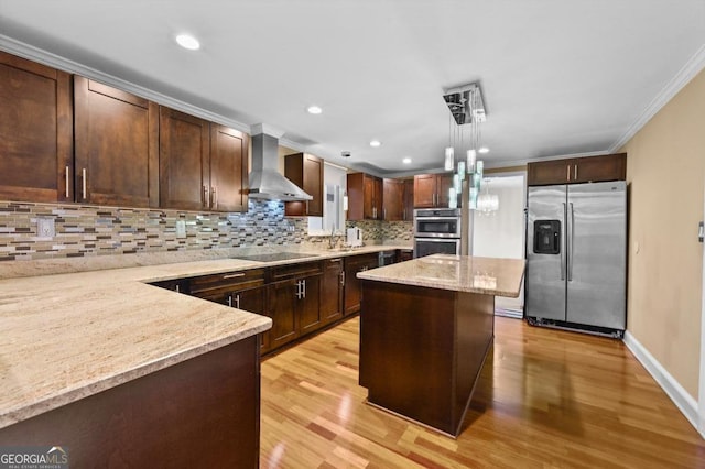 kitchen with light stone counters, decorative light fixtures, a center island, stainless steel appliances, and wall chimney range hood