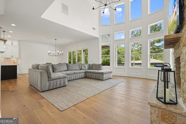 living area featuring light wood-style floors, visible vents, and a chandelier