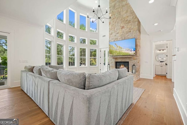 living room with a fireplace, wood finished floors, an inviting chandelier, and baseboards