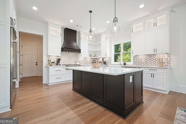 kitchen featuring glass insert cabinets, premium range hood, white cabinetry, and light countertops