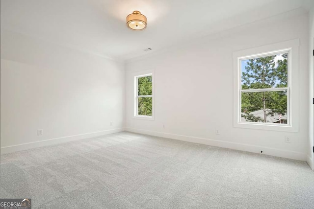 unfurnished room featuring light colored carpet and baseboards