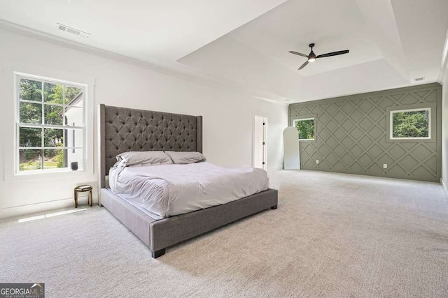 bedroom featuring ceiling fan, light colored carpet, an accent wall, visible vents, and a raised ceiling