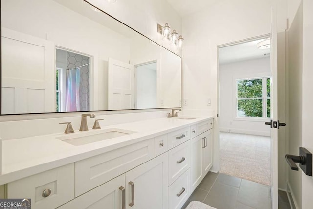 bathroom with double vanity, tile patterned flooring, baseboards, and a sink