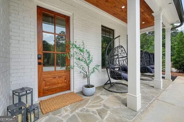 view of exterior entry with covered porch and brick siding