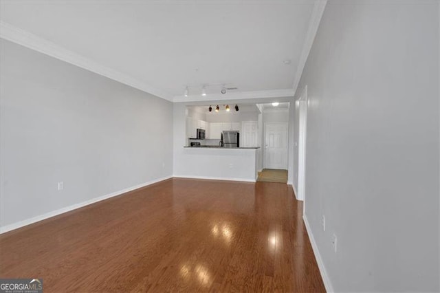 unfurnished living room featuring crown molding, track lighting, and dark hardwood / wood-style floors