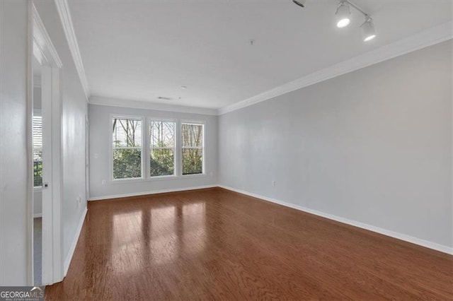 empty room featuring ornamental molding, dark hardwood / wood-style floors, and rail lighting