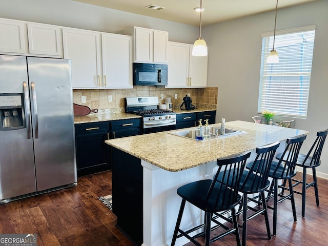 kitchen with stainless steel appliances, an island with sink, hanging light fixtures, and white cabinetry