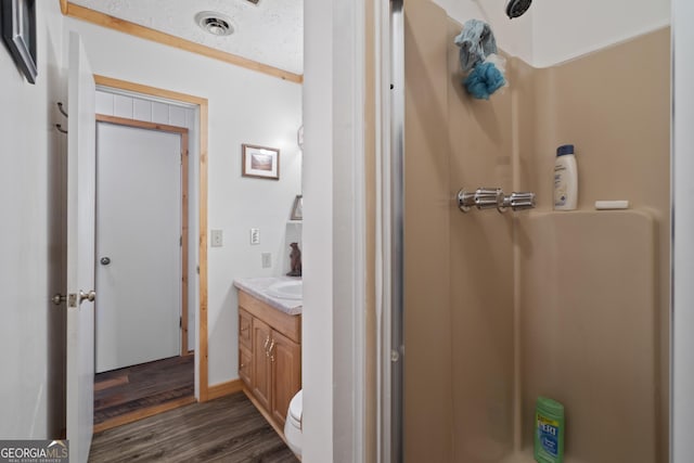 bathroom featuring vanity, hardwood / wood-style floors, toilet, and a shower