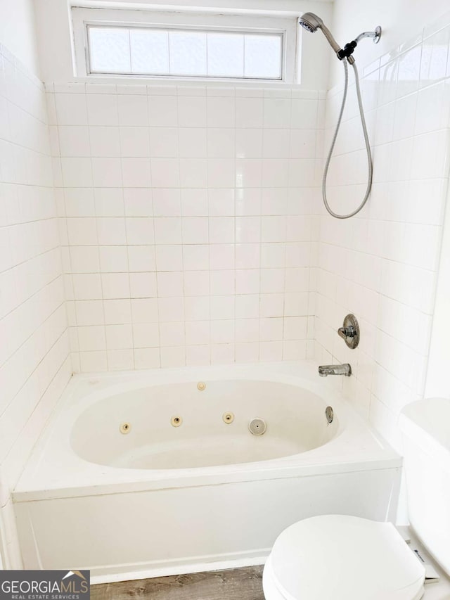 bathroom featuring toilet and tiled shower / bath