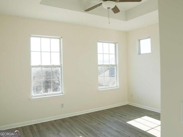 spare room featuring dark wood-type flooring, ceiling fan, and a tray ceiling