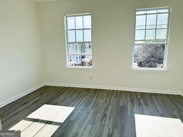 spare room with dark wood-type flooring and a healthy amount of sunlight