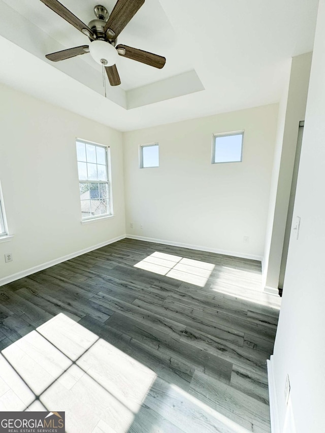 spare room featuring dark hardwood / wood-style floors, ceiling fan, and a tray ceiling