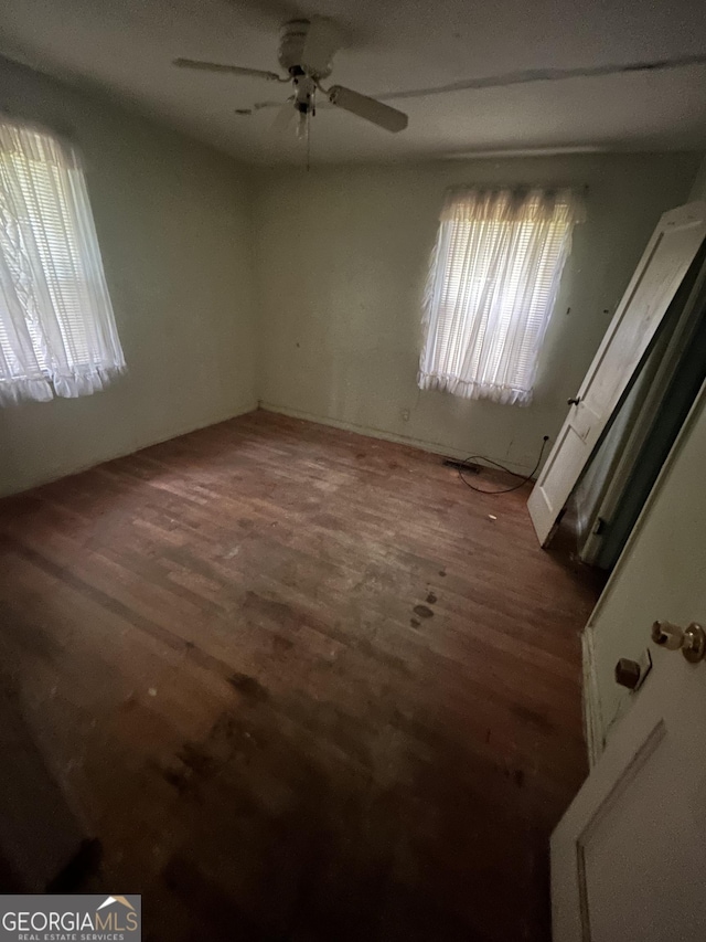 spare room with dark wood-type flooring and ceiling fan