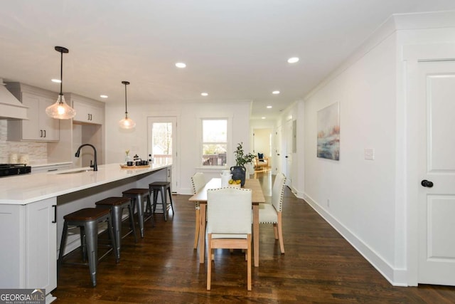 dining area featuring ornamental molding, sink, and dark hardwood / wood-style floors