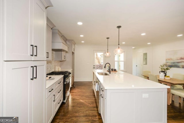 kitchen with sink, pendant lighting, stainless steel appliances, a kitchen island with sink, and decorative backsplash