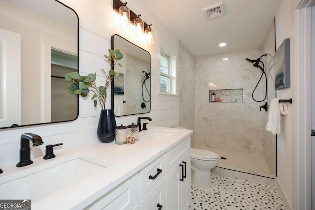 bathroom featuring tiled shower, vanity, and toilet