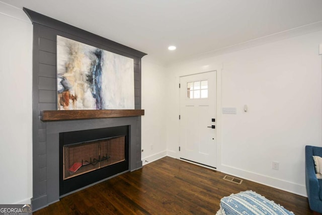 entrance foyer with crown molding, a large fireplace, and dark hardwood / wood-style floors