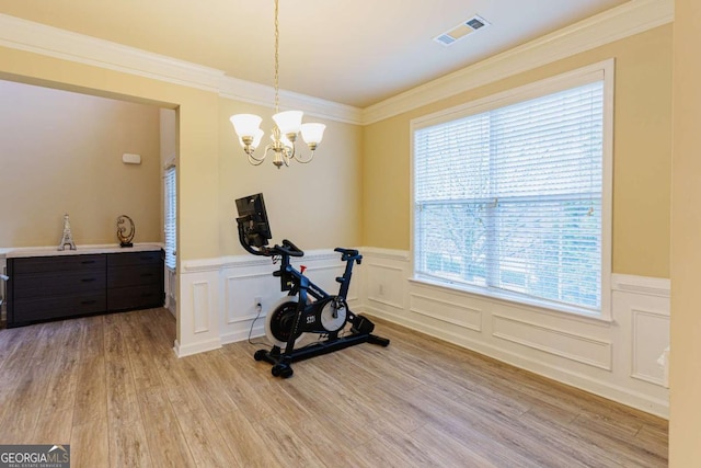 exercise area featuring an inviting chandelier, crown molding, and light hardwood / wood-style flooring