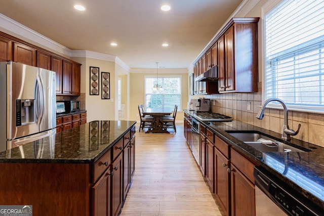 kitchen with sink, dark stone counters, ornamental molding, a center island, and stainless steel appliances