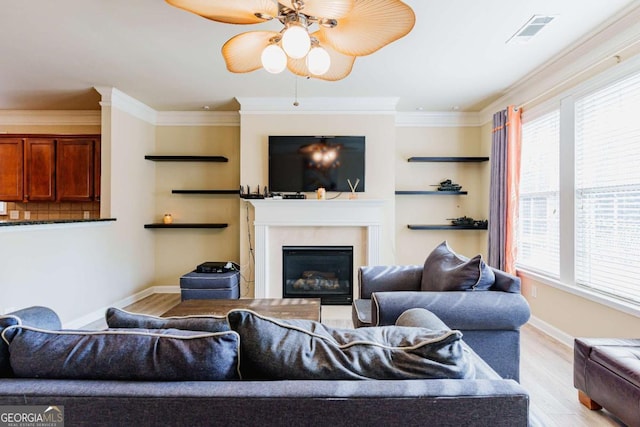 living room featuring ornamental molding, light hardwood / wood-style floors, and ceiling fan