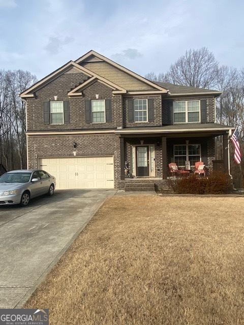 view of front of property featuring a garage, a front yard, and covered porch