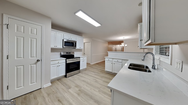 kitchen with sink, white cabinetry, hanging light fixtures, light wood-type flooring, and stainless steel appliances