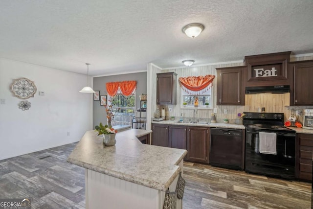 kitchen featuring dark brown cabinetry, sink, a center island, hanging light fixtures, and black appliances