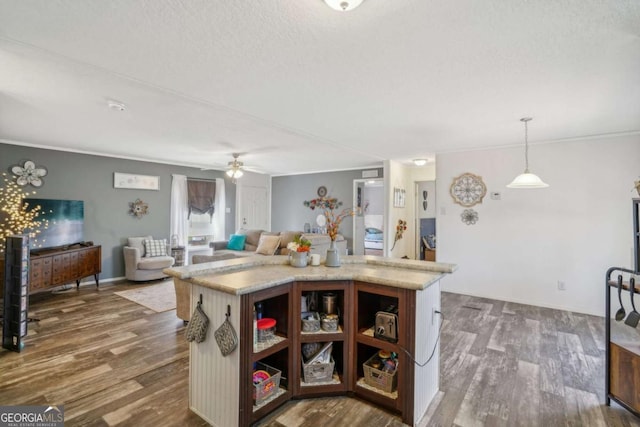 kitchen with pendant lighting, dark hardwood / wood-style flooring, ceiling fan, and a center island with sink