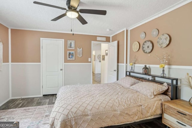 bedroom with ceiling fan, hardwood / wood-style flooring, ornamental molding, and a textured ceiling