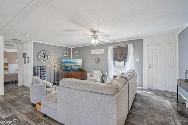 living room with crown molding, ceiling fan, dark hardwood / wood-style floors, and a textured ceiling