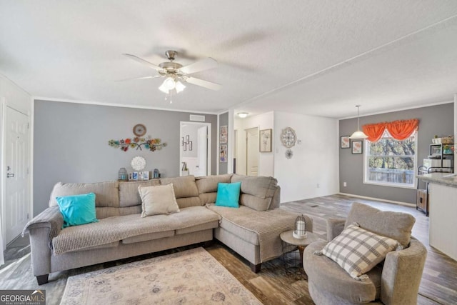 living room featuring hardwood / wood-style flooring, ornamental molding, and ceiling fan