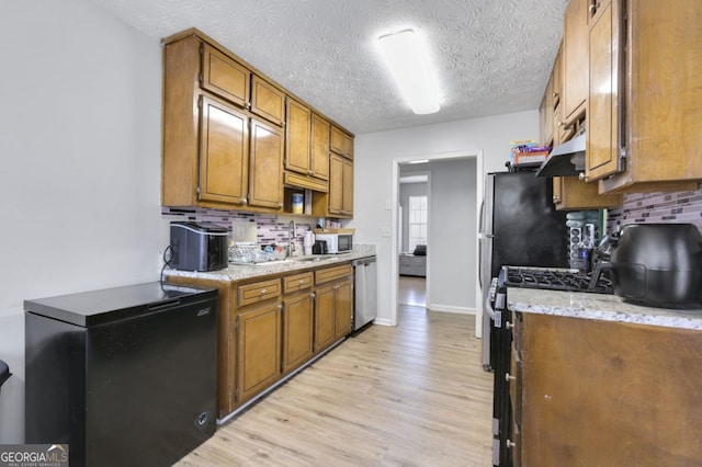 kitchen with decorative backsplash, stainless steel appliances, light hardwood / wood-style flooring, and a textured ceiling